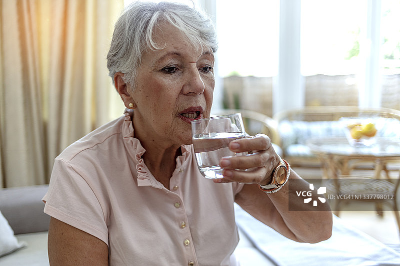 一个健康的老太太端着一杯水。图片素材