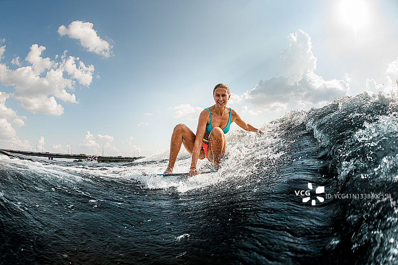 微笑的年轻女子在滑水板上冲下波浪图片素材