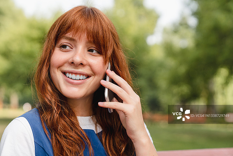 聪明的白种人年轻女子少女少女打电话给父母朋友，在智能手机上交谈，在公园森林的户外良好连接的在线交流。图片素材