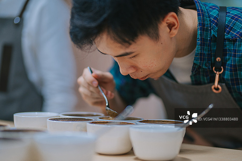 亚洲华人男专业咖啡师品级表演拔杯弯下腰近距离闻咖啡图片素材