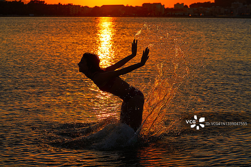 女孩泼水手在日落的海滩图片素材