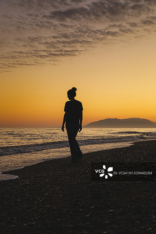 一个女人站在日落的海边图片素材