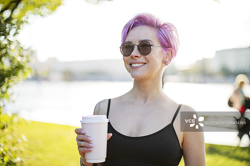 一个年轻的成年女子在公园里喝着咖啡图片素材