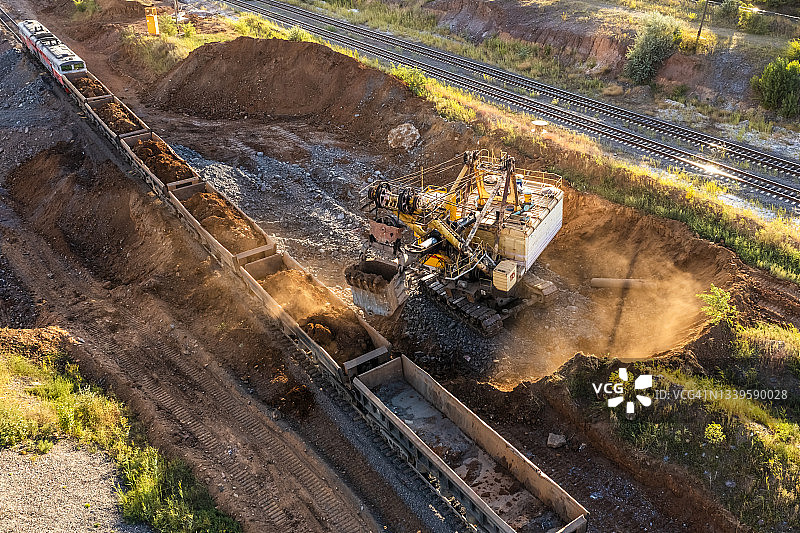 大型挖掘机将铁矿石装载到火车车厢中图片素材