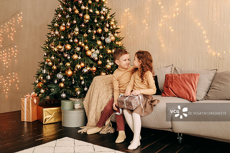 快乐有趣的小孩，青少年，朋友在家里玩得很开心，赠送礼品盒，装饰圣诞树，在舒适的房子里庆祝圣诞节图片素材