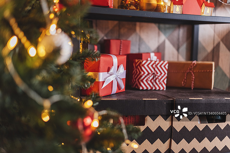 礼品盒上有一个大大的红色蝴蝶结，背景是闪烁的派对灯光。奢华的新年礼物。圣诞礼物。圣诞节背景与礼品盒。圣诞节的庆祝活动图片素材