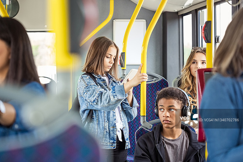 女孩在公交车上使用智能手机图片素材