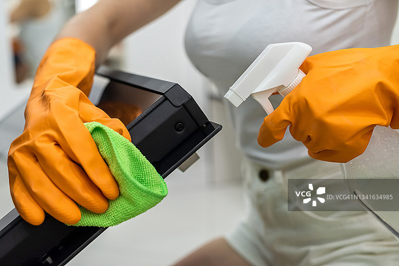 女手戴手套用清洁剂清洗厨房烤箱图片素材