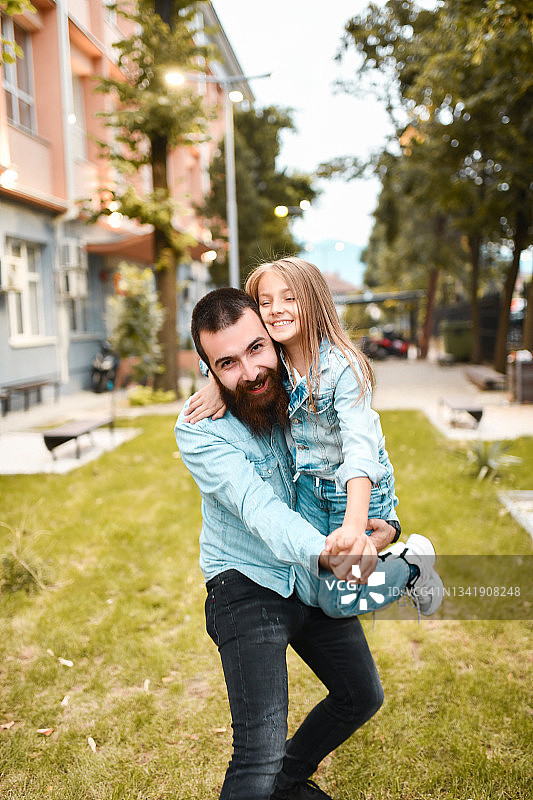 微笑的父亲抱着女儿在公园外面跳舞图片素材