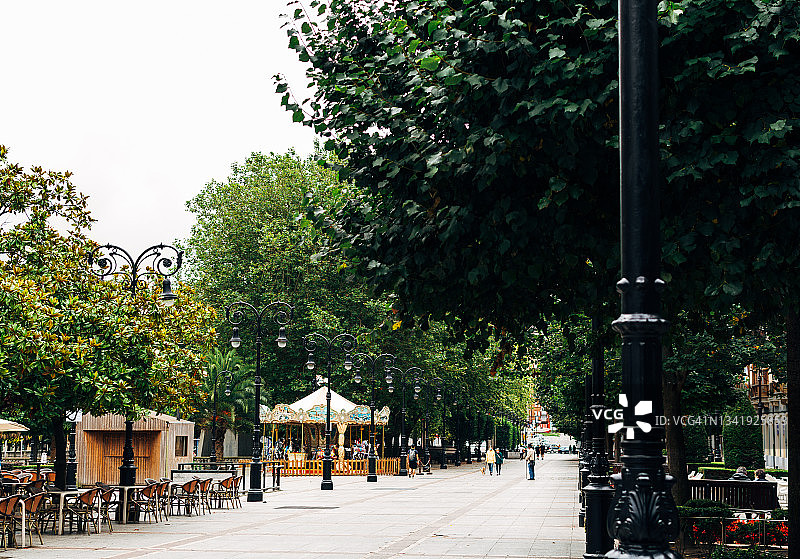 步行街的城市，咖啡馆露台和旋转木马，树木在阳光明媚的日子图片素材