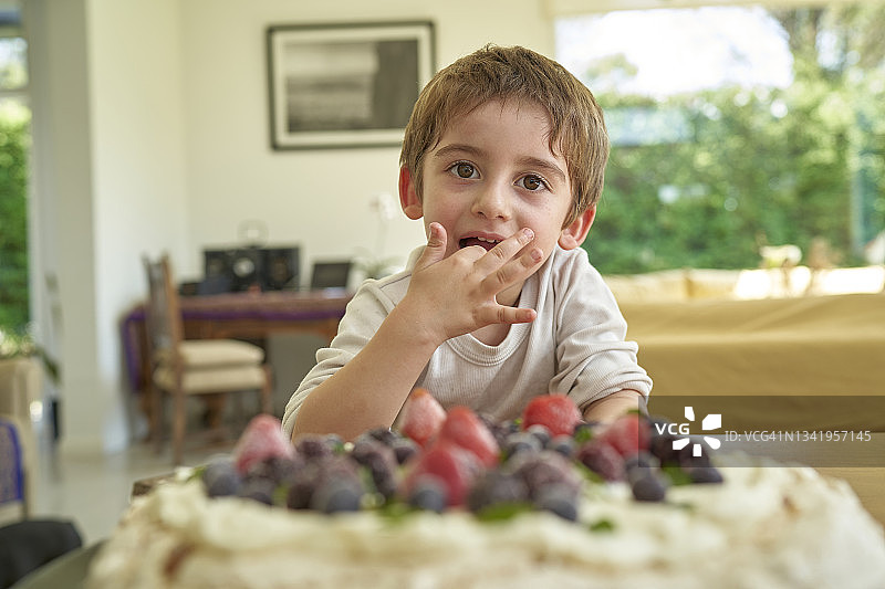 拉丁男孩在家里吃着蛋糕。图片素材