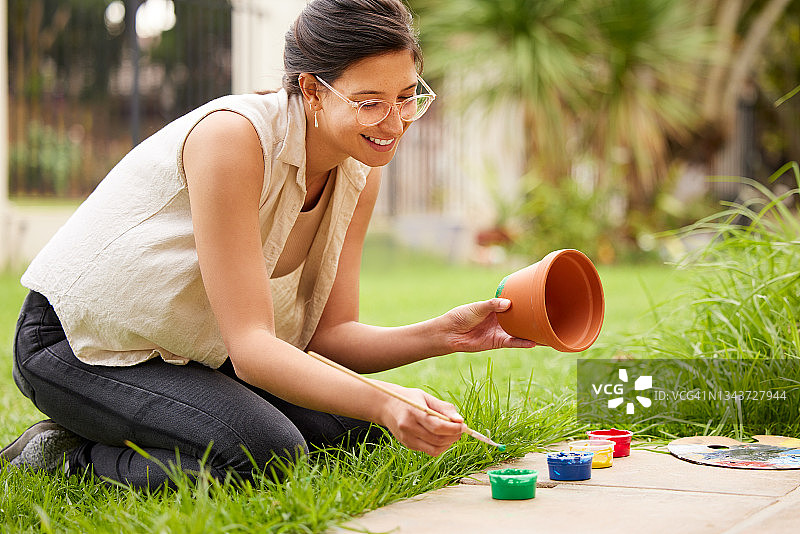 一个年轻的女人在家里的花园里画一个花盆图片素材