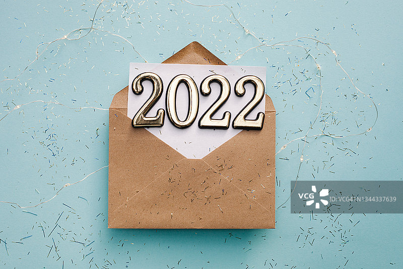 2022年新年贺卡。第2022号纸制信封，蓝色背景上有五彩纸屑。图片素材