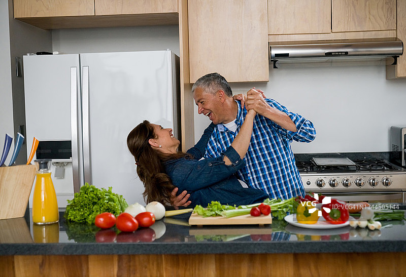 浪漫的老夫妇一起在家做饭，在厨房跳舞图片素材