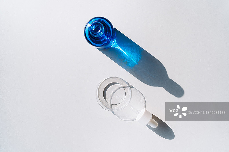 装有面部血清和移液管的蓝色玻璃瓶，置于有盖培养皿中，灰色背景。化妆品实验室研究的概念。摄影平铺风格图片素材