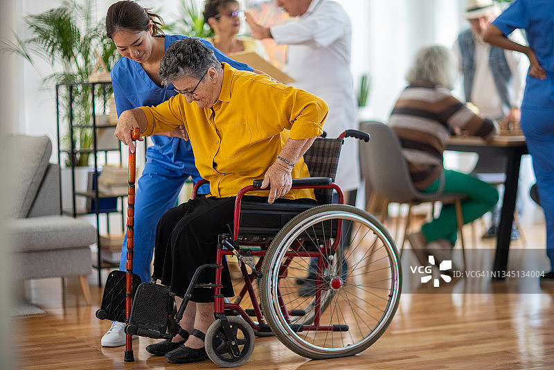 在养老院，女护士帮助老年妇女从轮椅上站起来图片素材