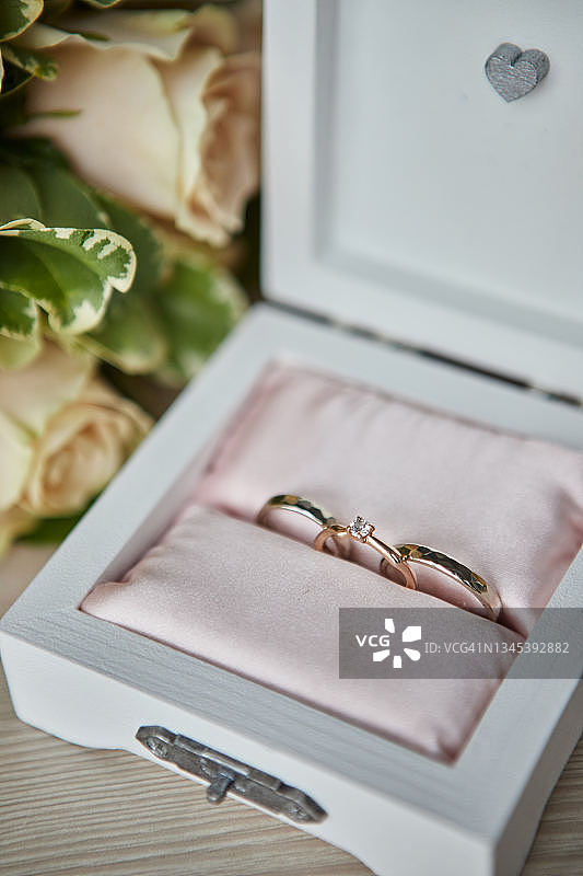 结婚戒指放在一个漂亮的盒子上，盒子里有鲜花作为新娘的配饰图片素材