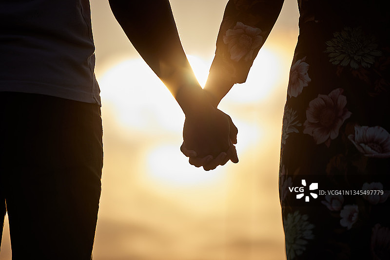 拍摄到一对不认识的情侣手牵着手看日落图片素材