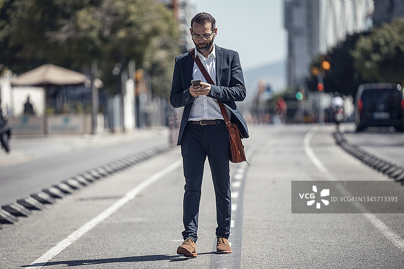 男性商务人士在城市里走路时使用手机图片素材