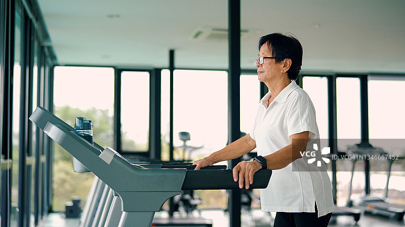 亚洲资深女性在跑步机上进行步行锻炼。图片素材