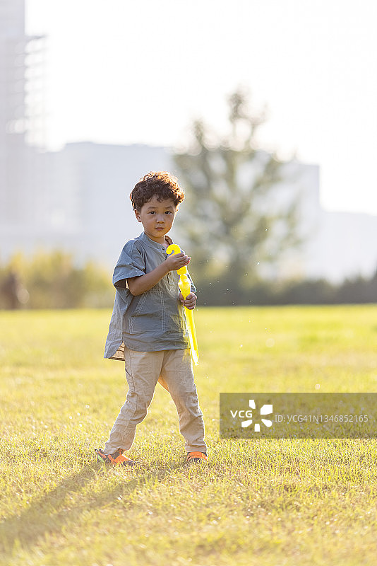 一个小男孩在公园里玩肥皂泡图片素材