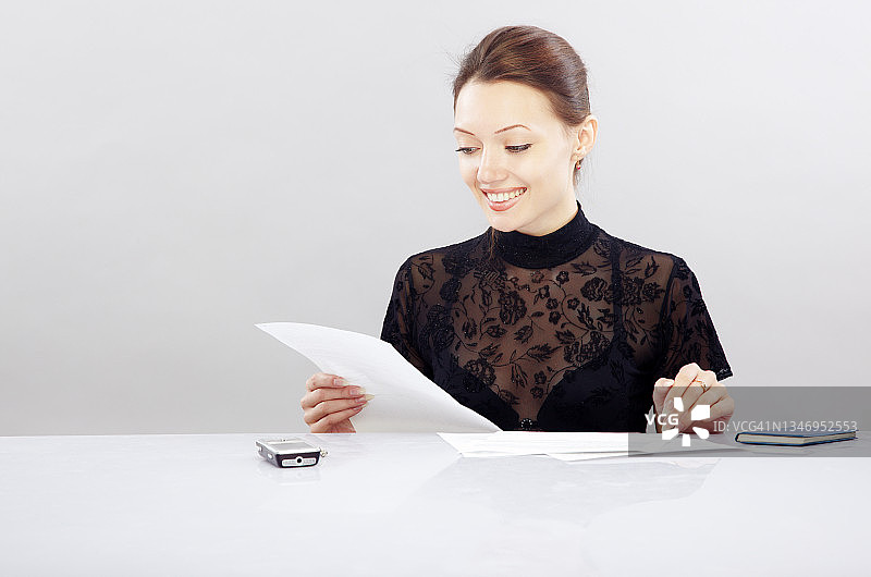 微笑的女人坐在办公桌前处理文件图片素材