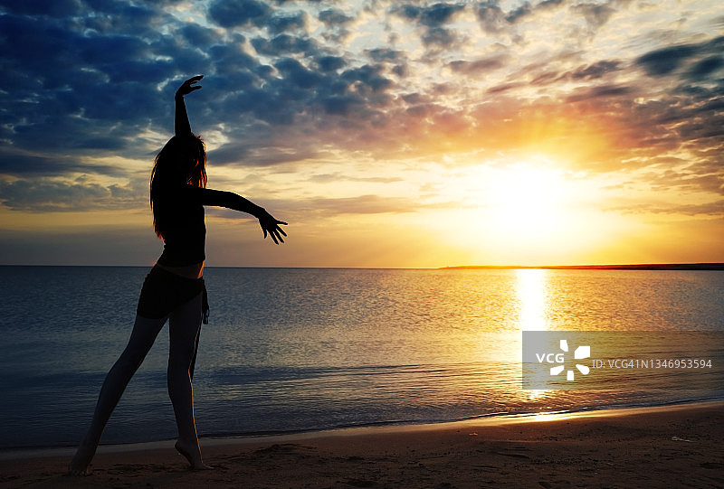 日落时分在海边跳舞的女人图片素材