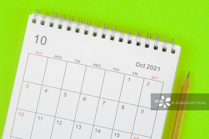 日历桌2021年10月，顶部视图日历组织者规划和铅笔在绿色背景。业务计划约会会议的概念图片素材