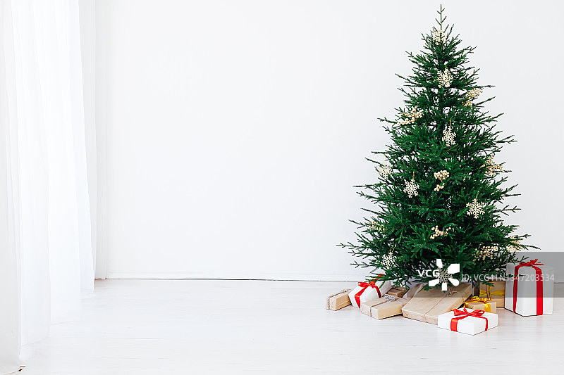 在一间有窗户的白色房间里，挂着新年礼物的圣诞树图片素材