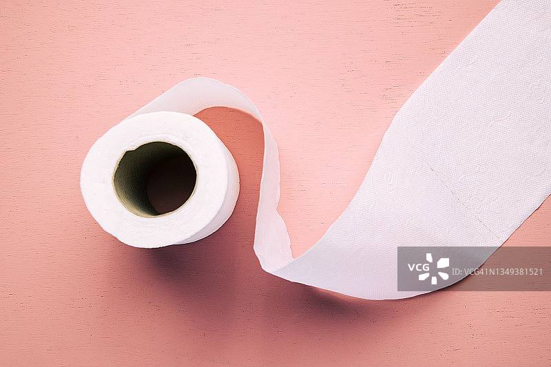 卫生纸卷照片在最小的风格复制空间，干净的软卫生纸卷浅粉色的背景。微距镜头。图片素材