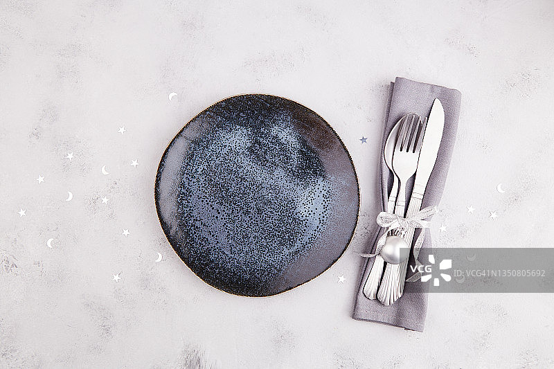 圣诞节或新年餐桌布置。盘子，银器，浅灰色背景上的装饰。准备节日晚餐图片素材