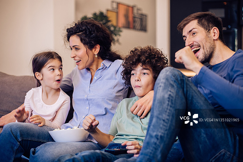 一个幸福的家庭在看电视上有趣的节目图片素材
