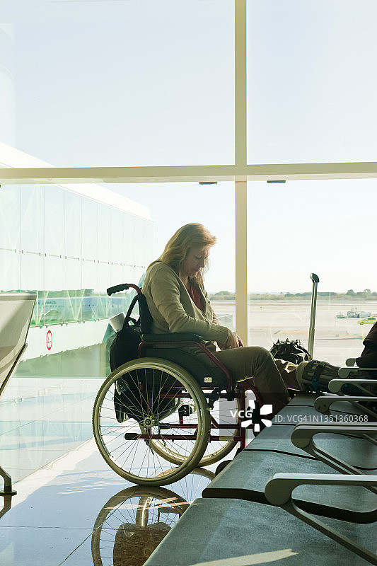 残疾和痛苦的妇女坐在轮椅在机场等待图片素材