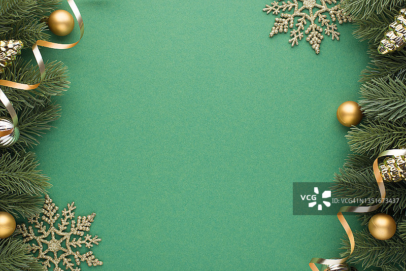 顶部视图照片的金色和银色的圣诞树球玩具锥形雪花和松枝上的蛇形线在孤立的绿色背景与copyspace图片素材