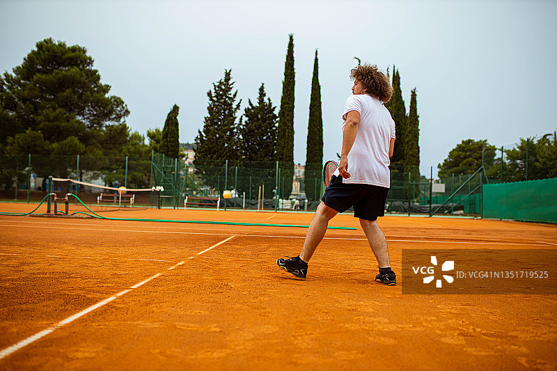 在他的网球比赛中，专注的男网球运动员等待一个发球回球图片素材