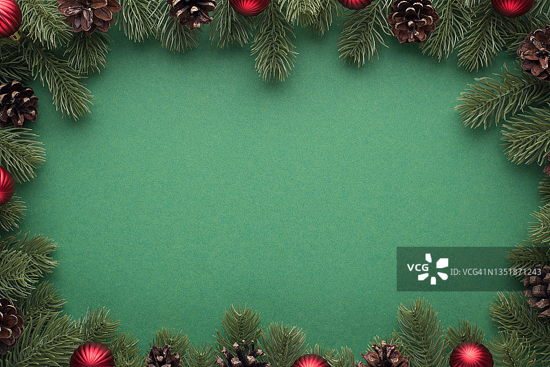 顶部视图照片的松枝与球果和红色的圣诞树球孤立的绿色背景与空白在中间图片素材