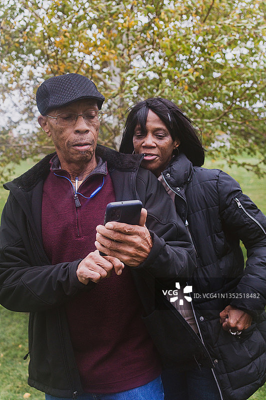成年老年夫妇在公园里使用手机图片素材