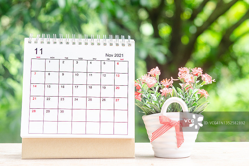 日历桌2021年11月，日历规划和室内植物与绿树自然背景木桌。图片素材