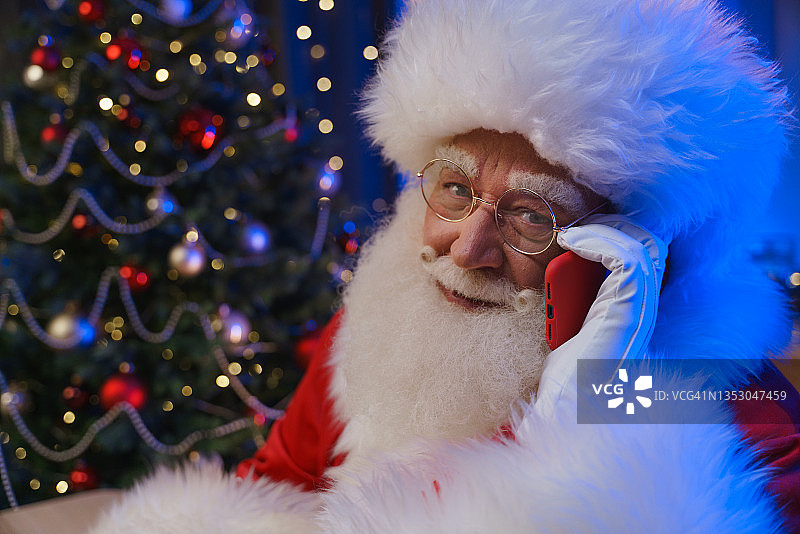 微笑的圣诞老人正在讲手机。图片素材