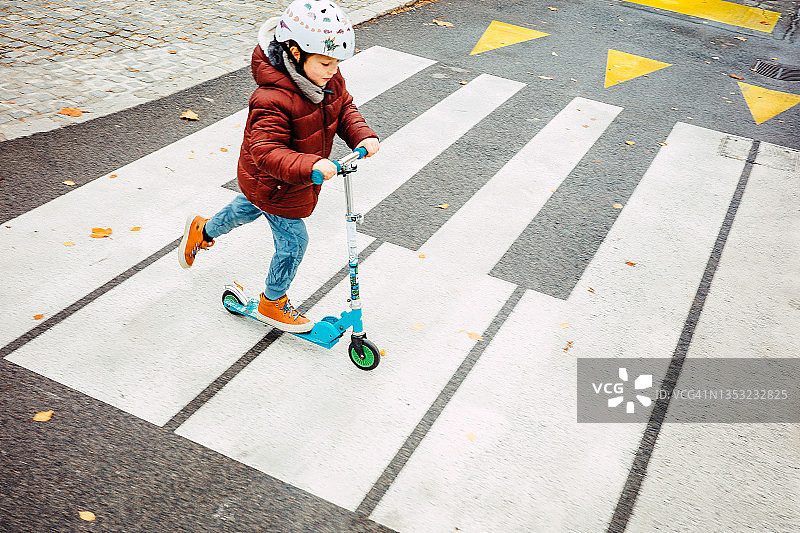 一个小孩骑着摩托车过马路图片素材