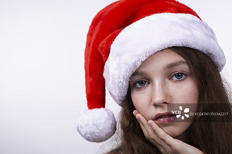 一个美丽可爱的牙齿微笑的年轻女子的肖像穿着圣诞老人的帽子在白色的背景图片素材