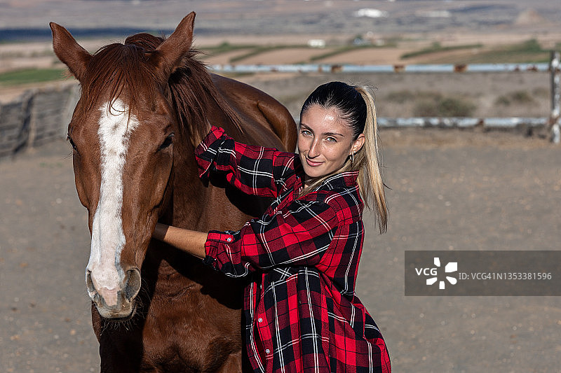 在户外马厩里，一位女骑手和她的纯种马合影图片素材