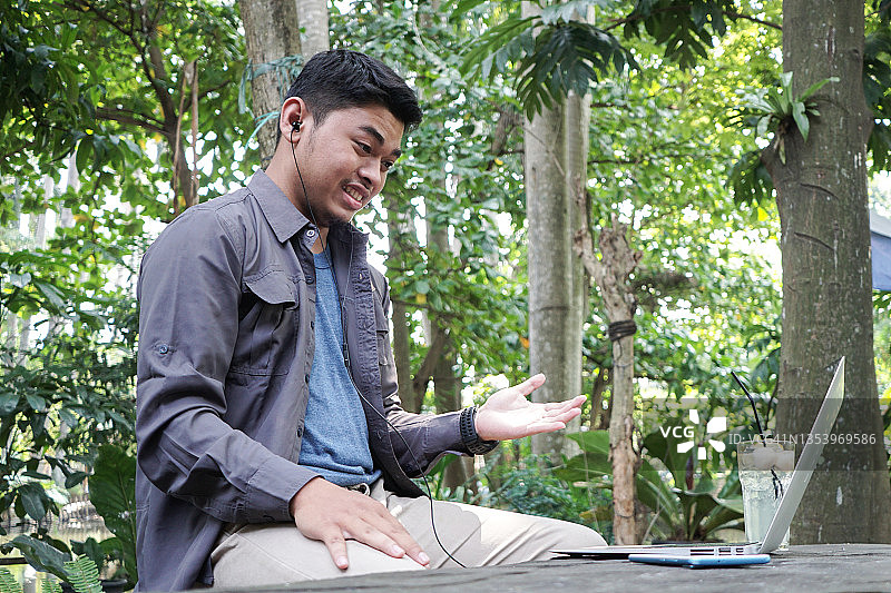 亚洲年轻人在户外用笔记本电脑进行视频会议图片素材