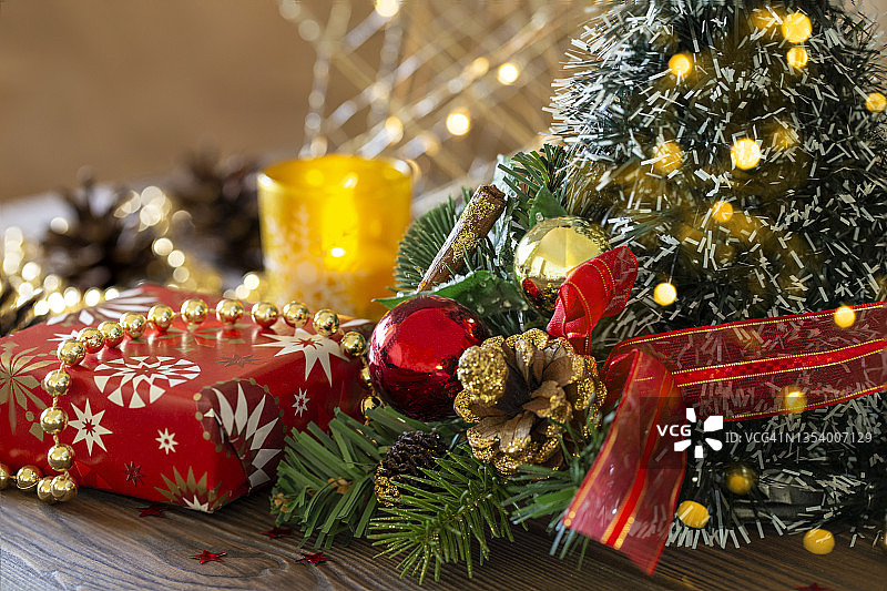 特写圣诞节日背景与圣诞树装饰球和松果和珠子，礼物，金色的灯在木桌上，特写。图片素材