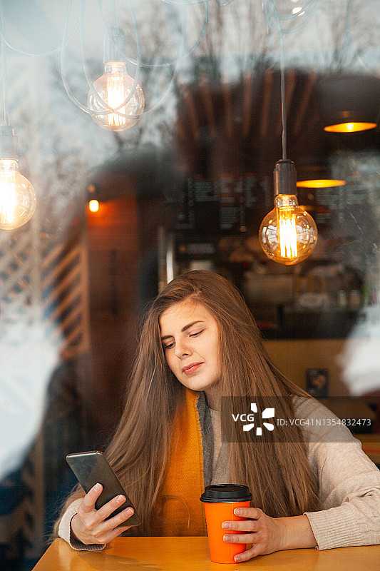 微笑的女人在惬意的咖啡馆浏览智能手机图片素材