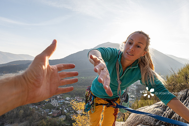 女登山运动员伸出手来寻求队友的帮助图片素材