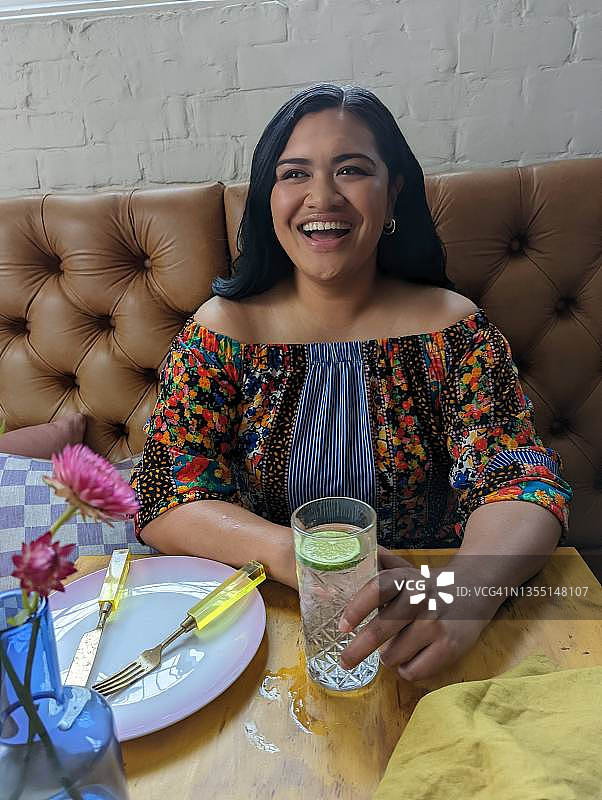 一位年轻女子在餐馆里用手机微笑图片素材