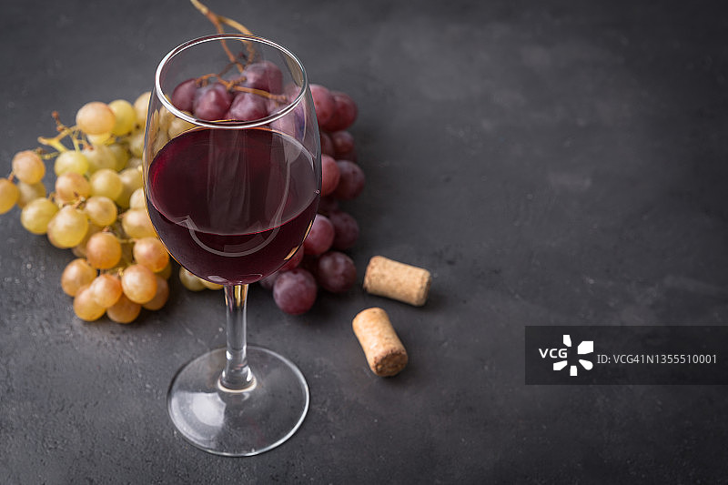黑石桌上放着红、白葡萄酒和新鲜的葡萄。图片素材