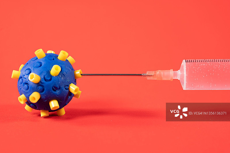 一枚冠状病毒和一枚装有疫苗的注射器。图片素材