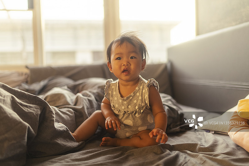 近面部表情肖像亚洲女婴在舒适的床上玩图片素材